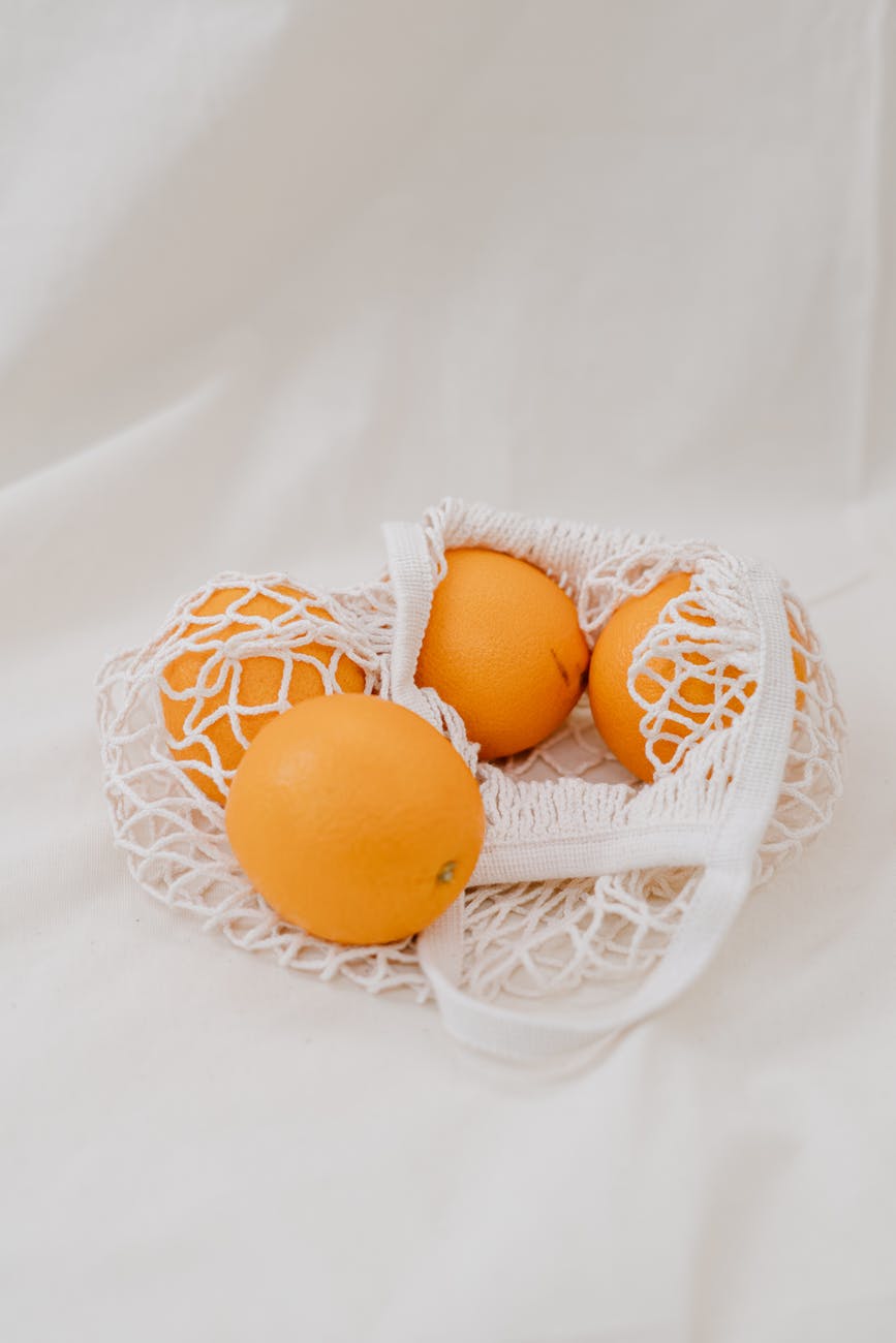 four yellow oranges eggs in white net
